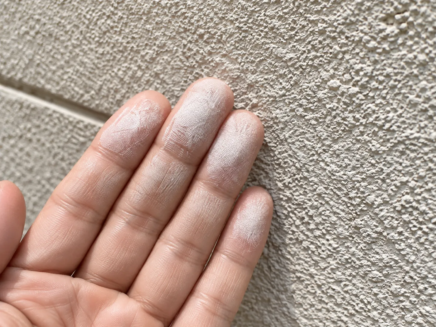 外壁を手で触ると白い粉が付着する現象。塗膜の劣化が進行しています。 チョーキング